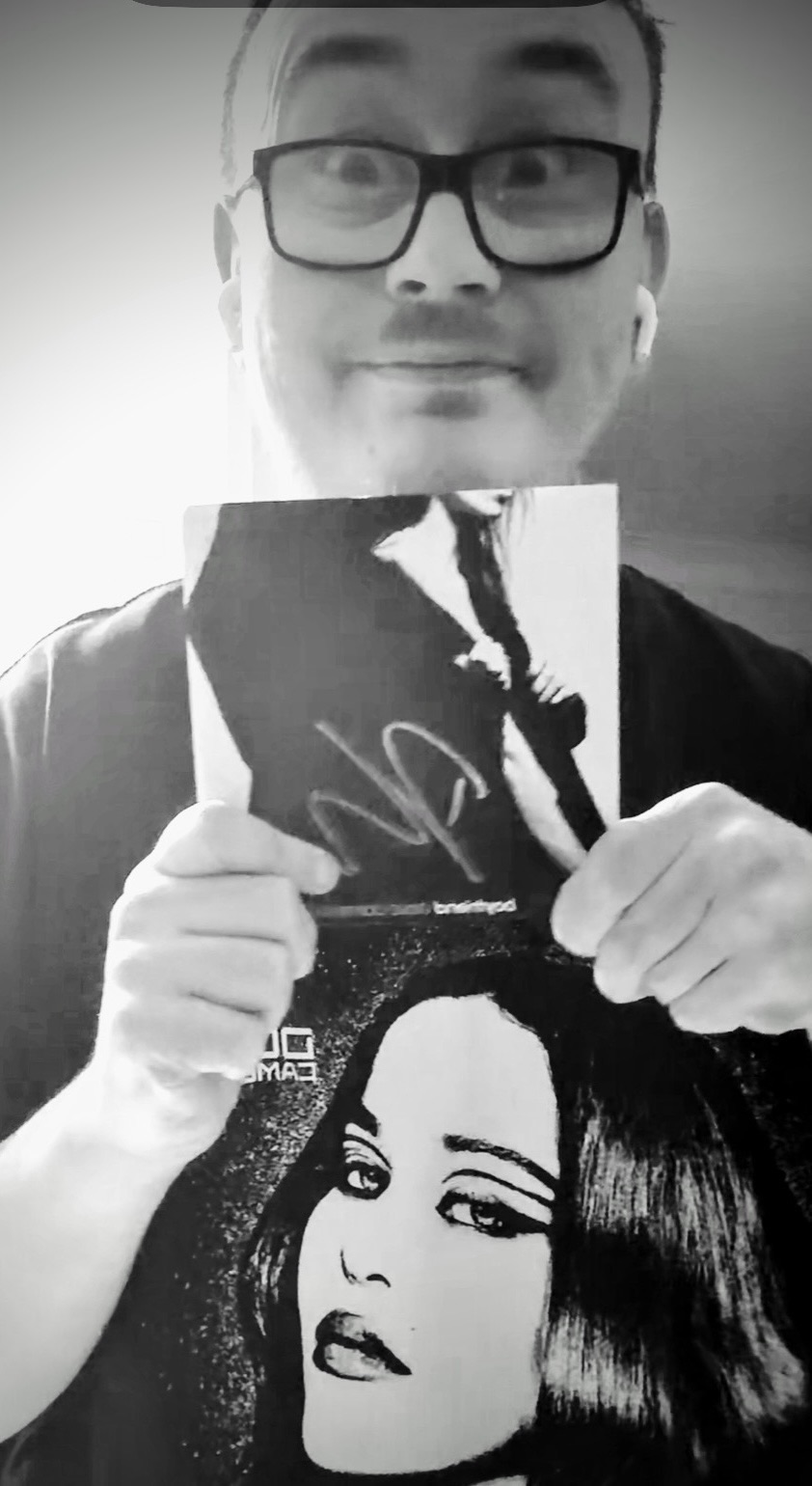 Tom Davies, DovelyTom, holding a signed Dove Cameron print